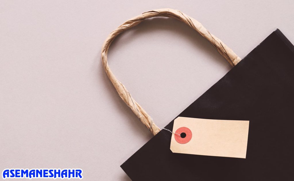 ساک دستی مشکی با دسته کاغذی و برچسب قیمت، نمایی نزدیک از بسته‌ بندی شیک و مدرن برای محصولات لوکس.