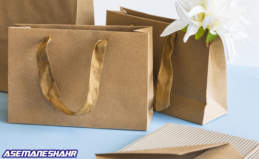 پاکت هدیه کرافت با بند روبانی طلایی و گل سفید | انتخابی خاص برای بسته‌ بندی کادوهای شیک