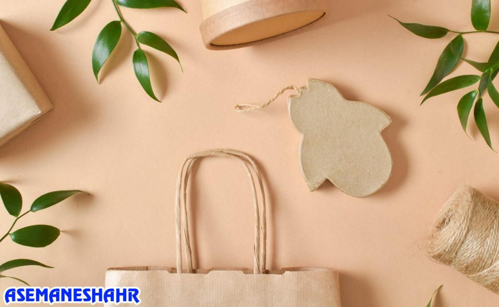 چیدمان زیبا از پاکت هدیه کرافت همراه برچسب فانتزی، طناب کنفی و برگ‌های سبز | مناسب بسته‌ بندی سازگار با محیط‌ زیست.