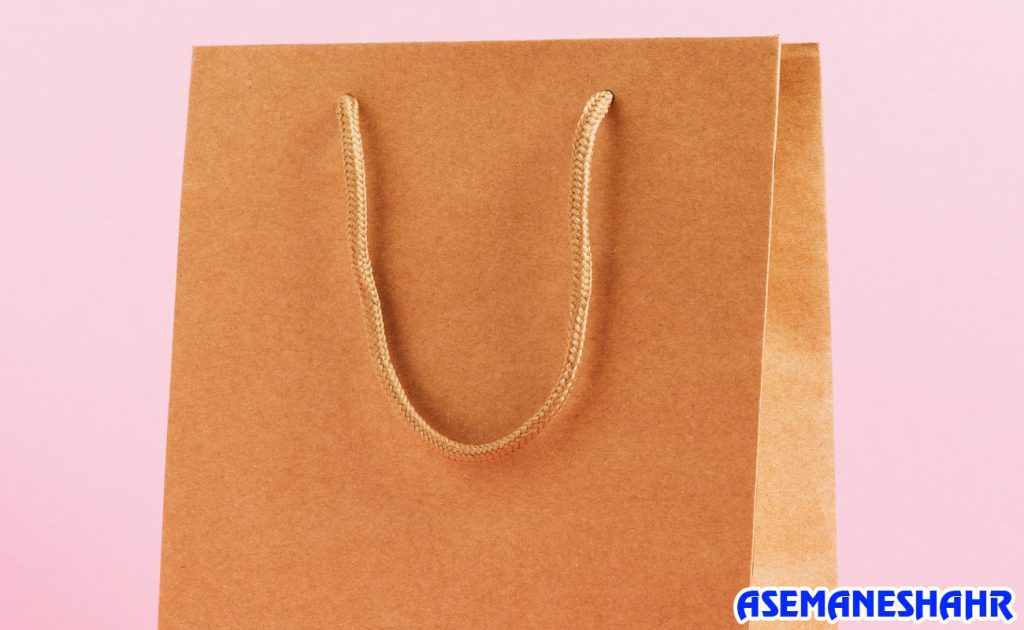 ساک دستی کرافت با دسته طنابی مقاوم و طراحی مینیمال، انتخابی زیبا و طبیعی برای هدیه، با پس‌ زمینه صورتی جذاب.
