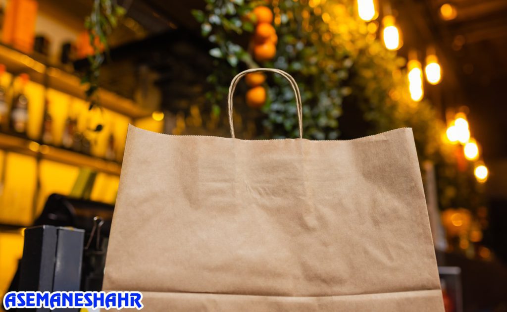 ساک دستی کرافت ساده در فضای کافی‌ شاپ با نور گرم | انتخابی خاص برای بسته‌ بندی هدیه و خرید روزمره.