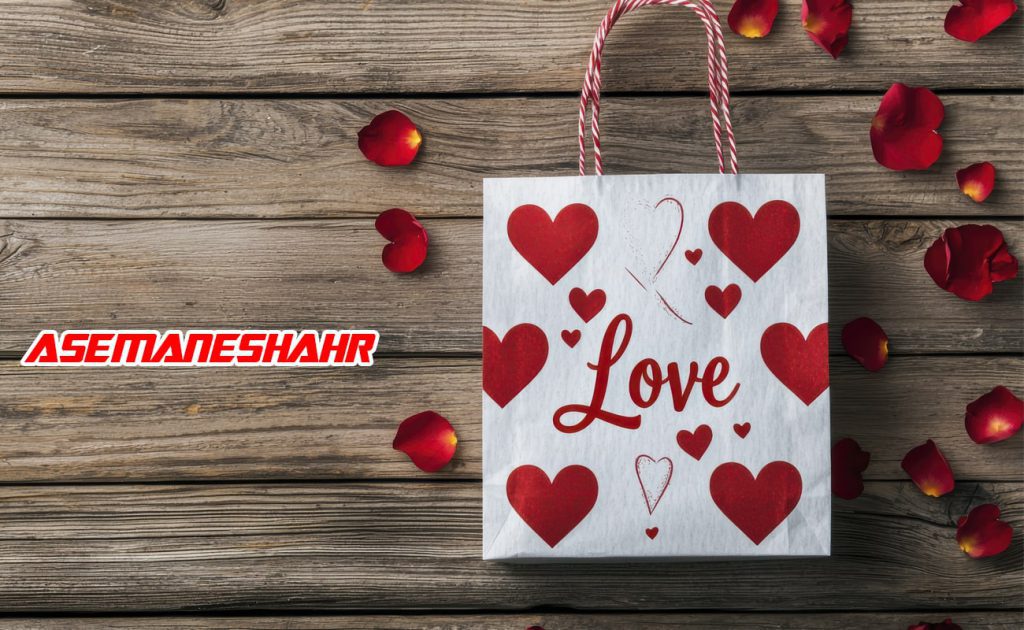 ساک دستی کاغذی با طراحی قلب‌ های قرمز و نوشته Love، همراه با دسته طنابی سفید و قرمز و تزئین گلبرگ‌های رز قرمز روی پس‌ زمینه چوبی.