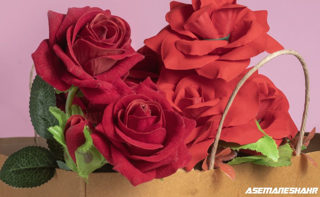 کیسه هدیه کاغذی تزئین‌ شده با گل‌های رز قرمز و برگ‌های سبز، مناسب برای هدایا و مناسبت‌های عاشقانه.