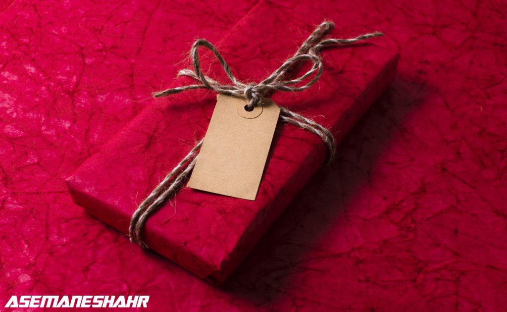 بسته بندی هدیه شیک با کاغذ قرمز و نخی طبیعی، شامل برچسب خام برای نوشتن پیام شخصی و مناسب جشنها و مناسبتها.