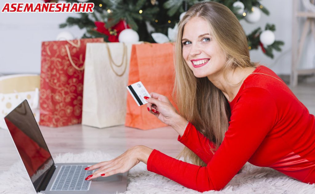 خرید آنلاین با لپ‌ تاپ، کارت بانکی و ساک‌ های هدیه رنگی.