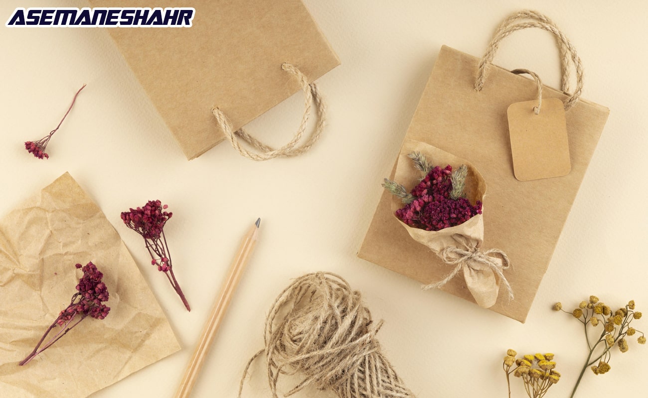 ایدههای بسته بندی هدیه شامل کیسه های کاغذی قهوهای با طرحهای مینیمال، گلهای خشک و نخ کنفی برای تزئین.