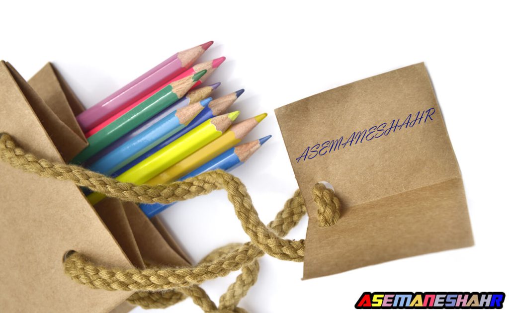 کیسه هدیه کاغذی با طراحی ساده و دسته کنفی، حاوی مدادهای رنگی، از مجموعه آسمانشهر.