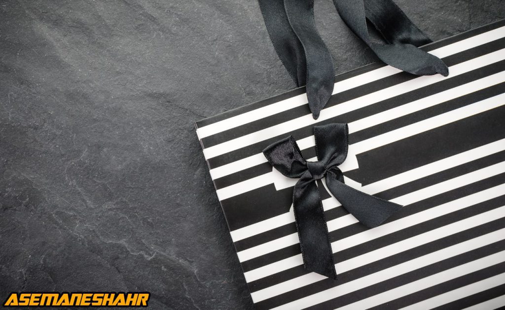 ساک دستی تبلیغاتی با طراحی راه‌ راه مشکی و سفید و پاپیون مشکی | انتخابی شیک برای بسته‌ بندی هدایا و محصولات لوکس.